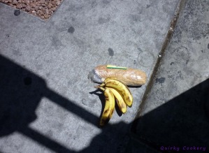 A bunch of 3 bananas and a wrapped ham and cheese sub on the ground in Las Vegas